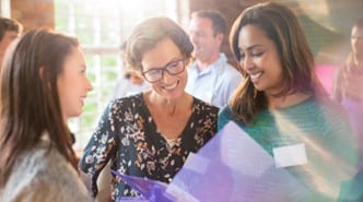 A group of women engaged in conversation, smiling and enjoying each other's company in a lively setting