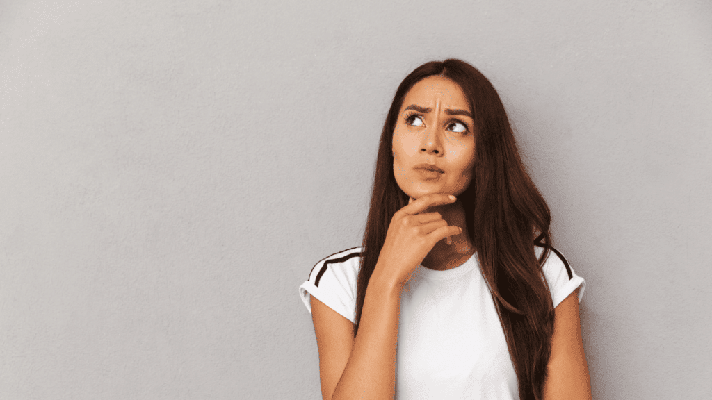 A person stands near a wall and looks very contemplative.