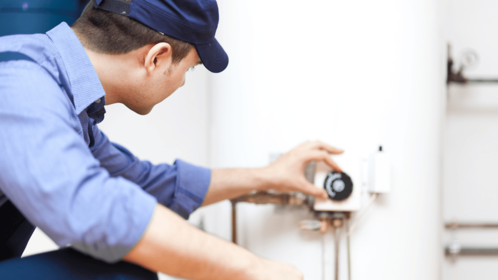 A professional plumber adjusts the dial on a water heater.