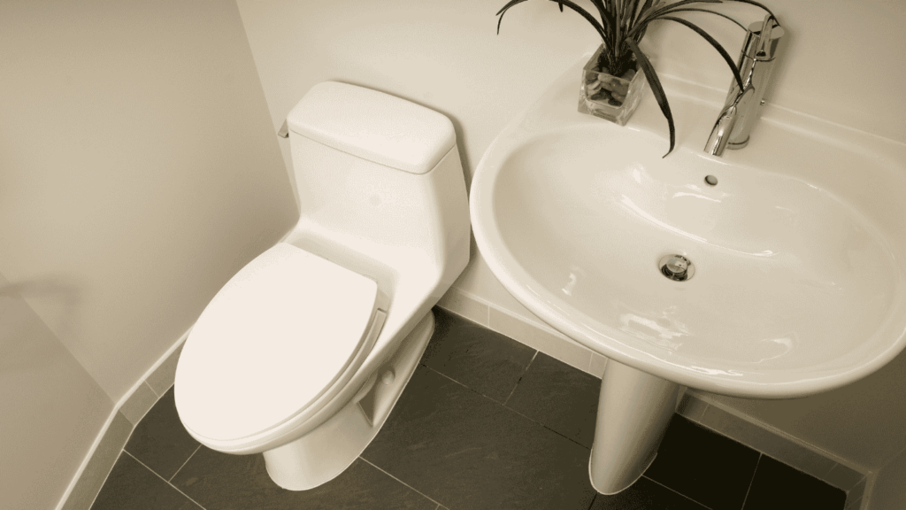 A small bathroom with a toilet, sink, and mirror.