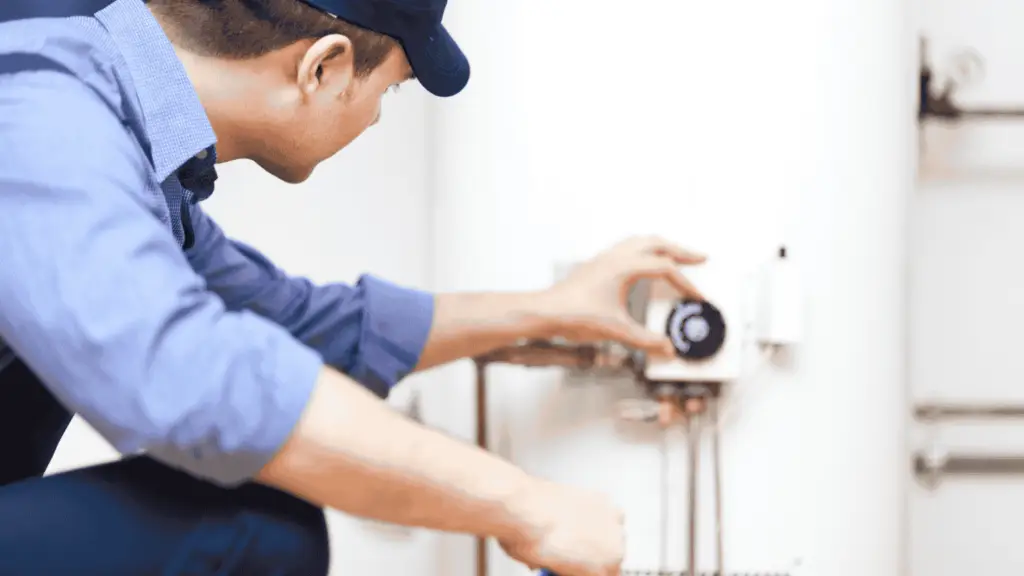 A plumber adjusts the dial on a water heater.